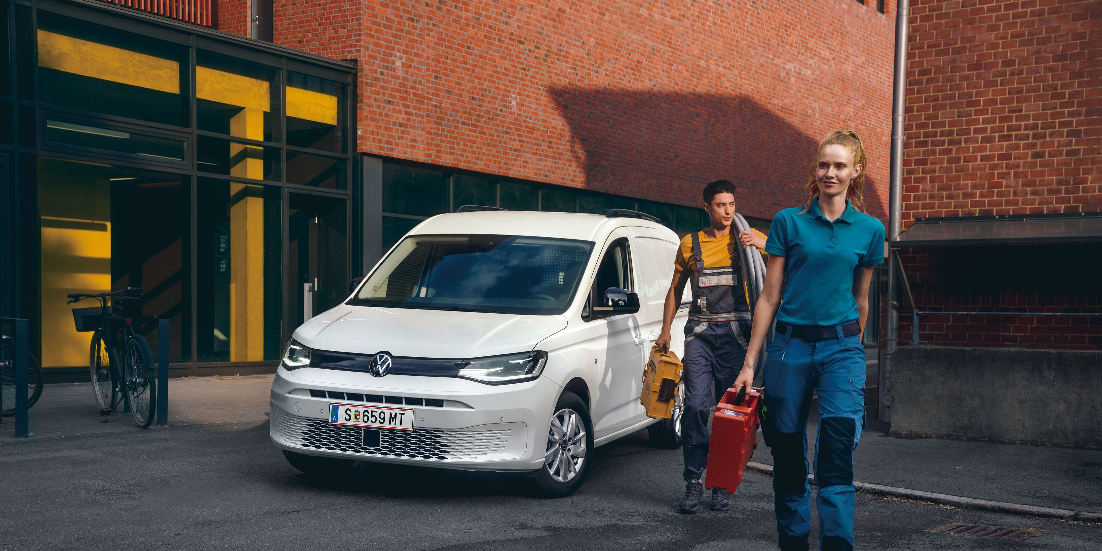 Ein Handwerker-Team vor einem weißen VW Caddy Cargo.