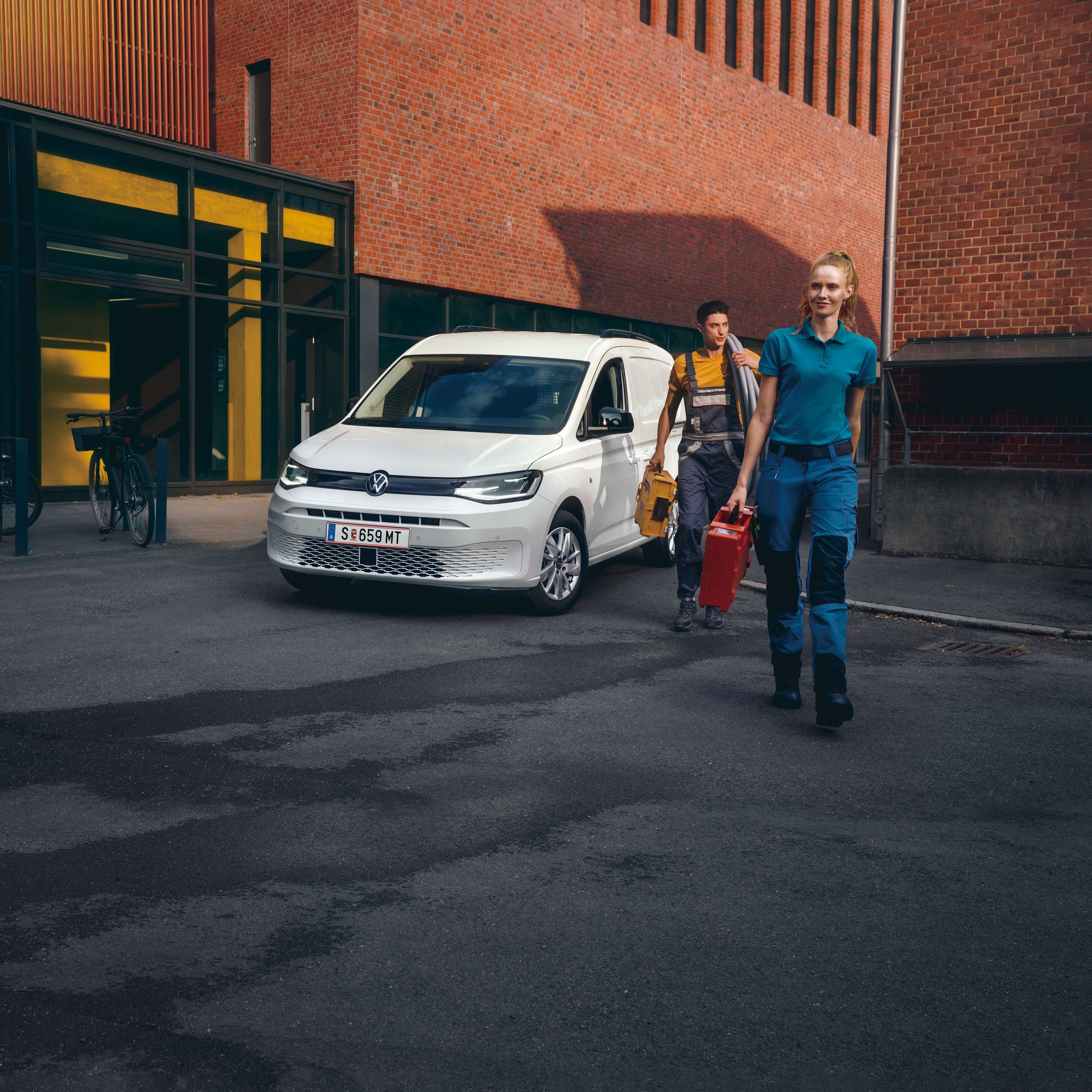 Ein Handwerker-Team vor einem weißen VW Caddy Cargo.