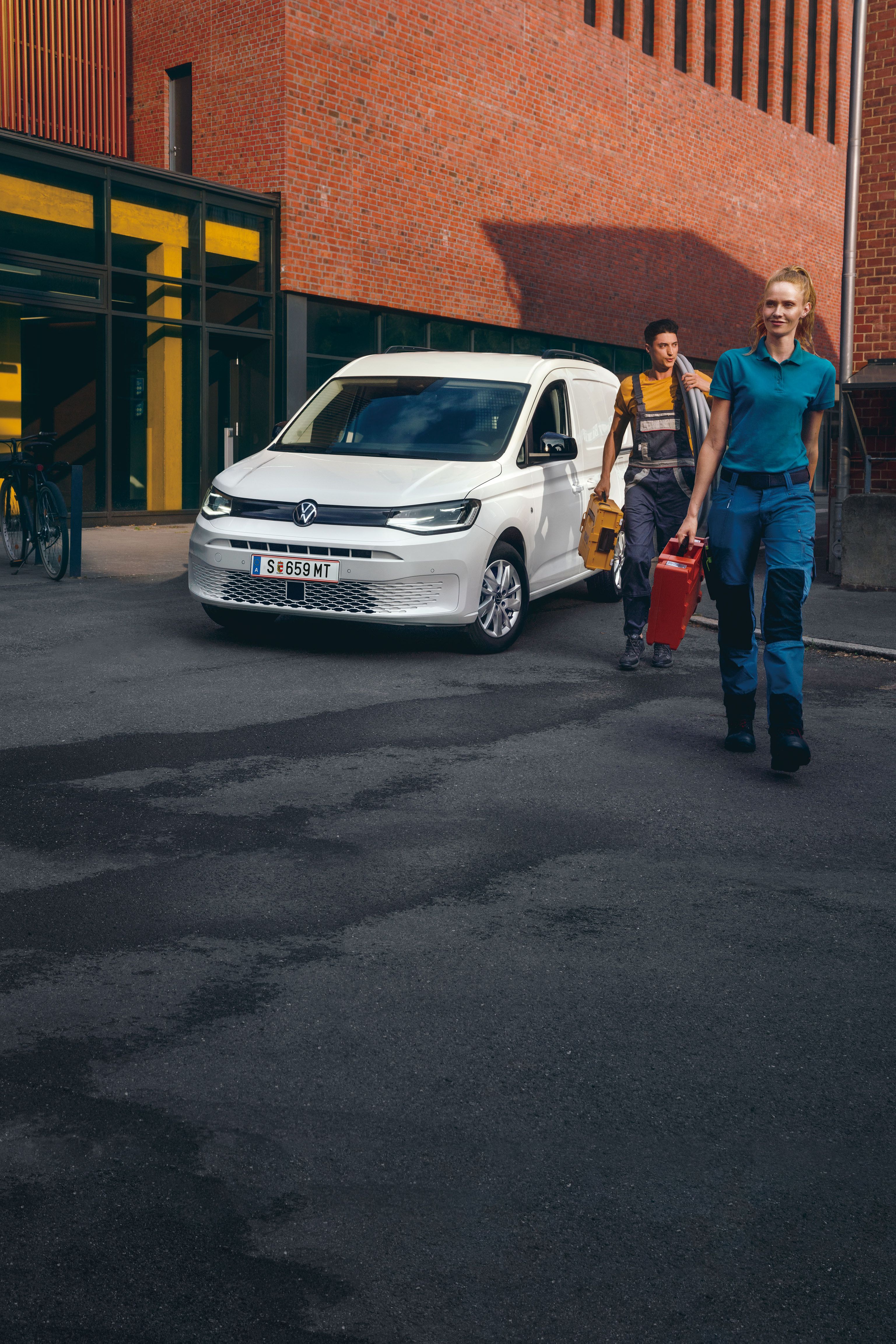 Ein Handwerker-Team vor einem weißen VW Caddy Cargo.