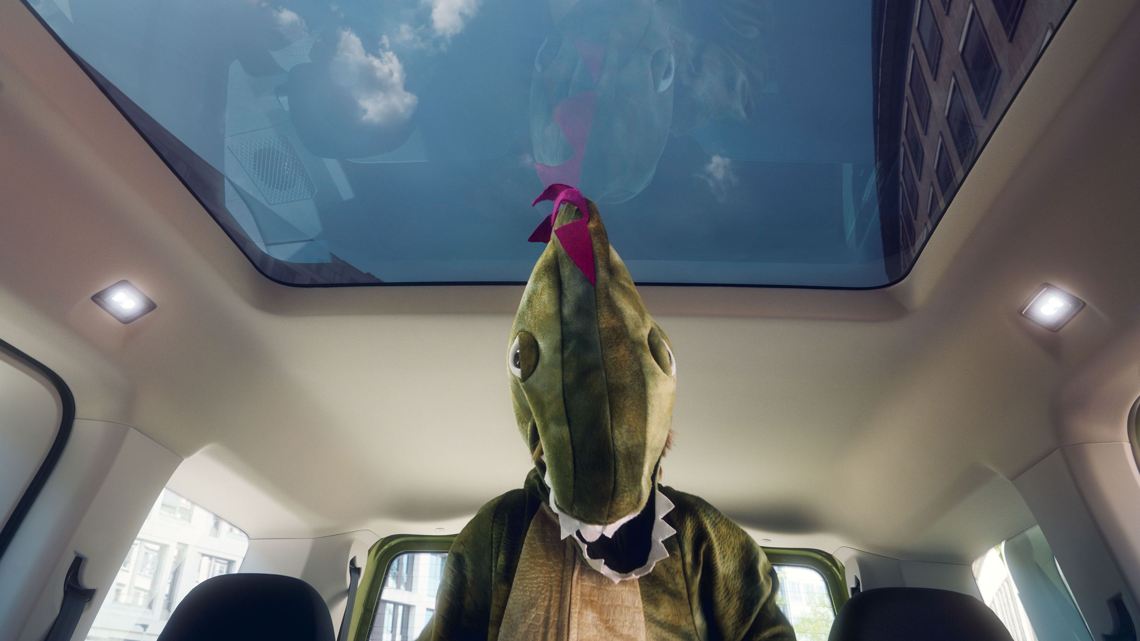Ein als Krokodil verkleidetes Kind sitzt in einem VW Caddy und schaut aus dem Panoramadach.