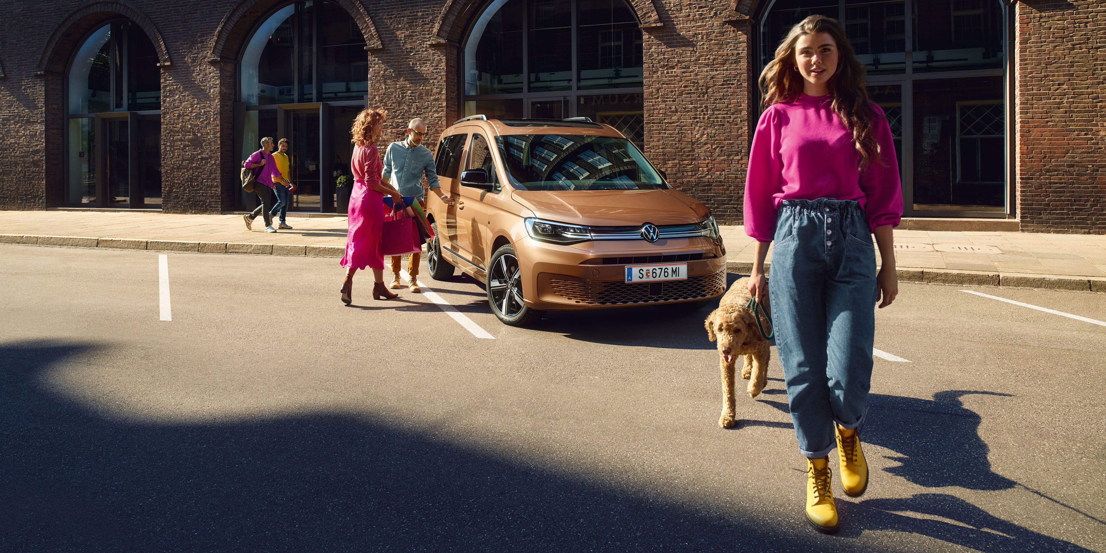 Eine Familie mit ihrem Hund mit einem VW Caddy.