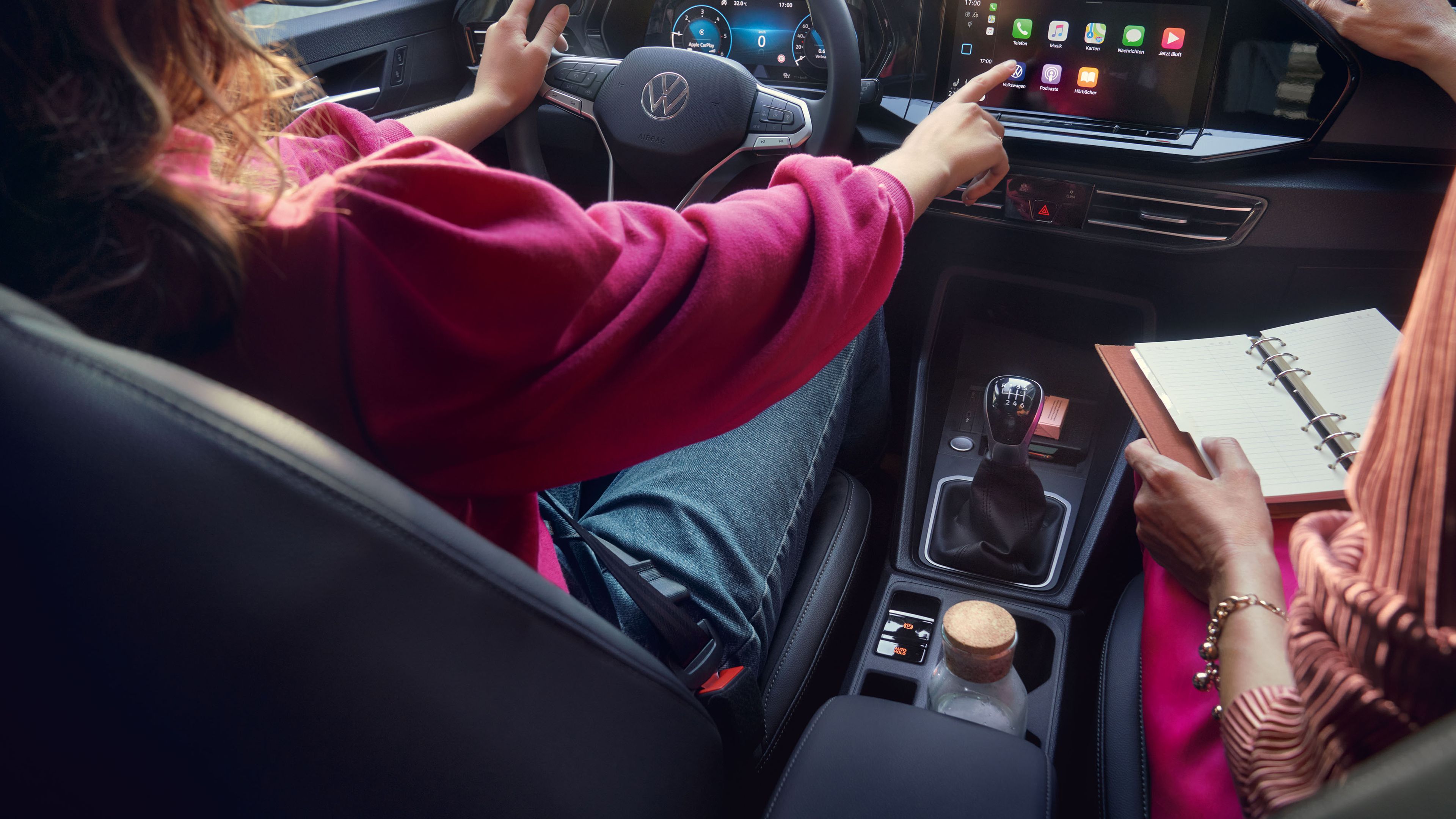 Zwei Frauen sitzen im VW Caddy und bedienen die Digitalanzeige.