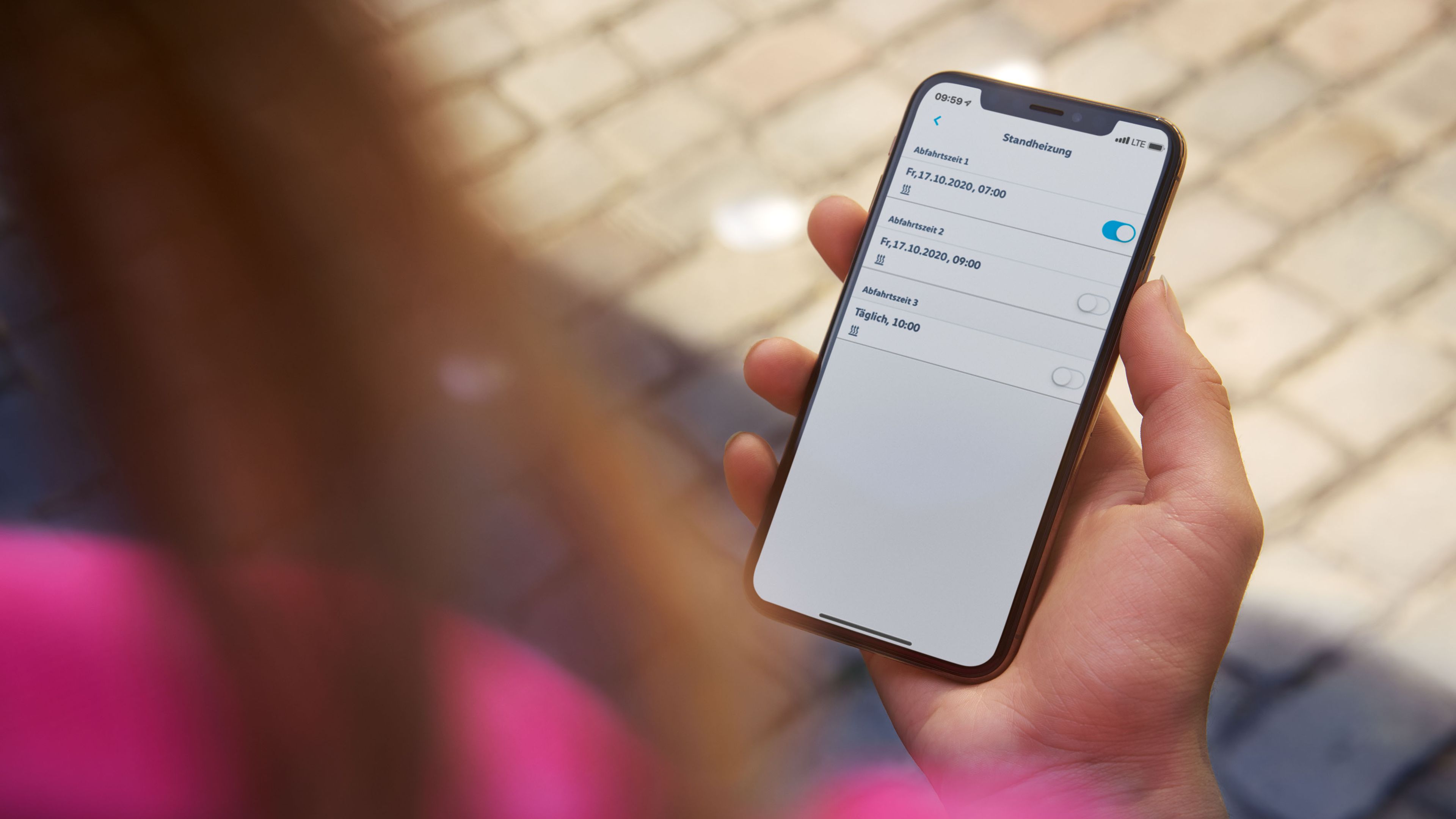 Eine Frau hält ein Smartphone mit geöffneter We-Connect-App in ihrer Hand.