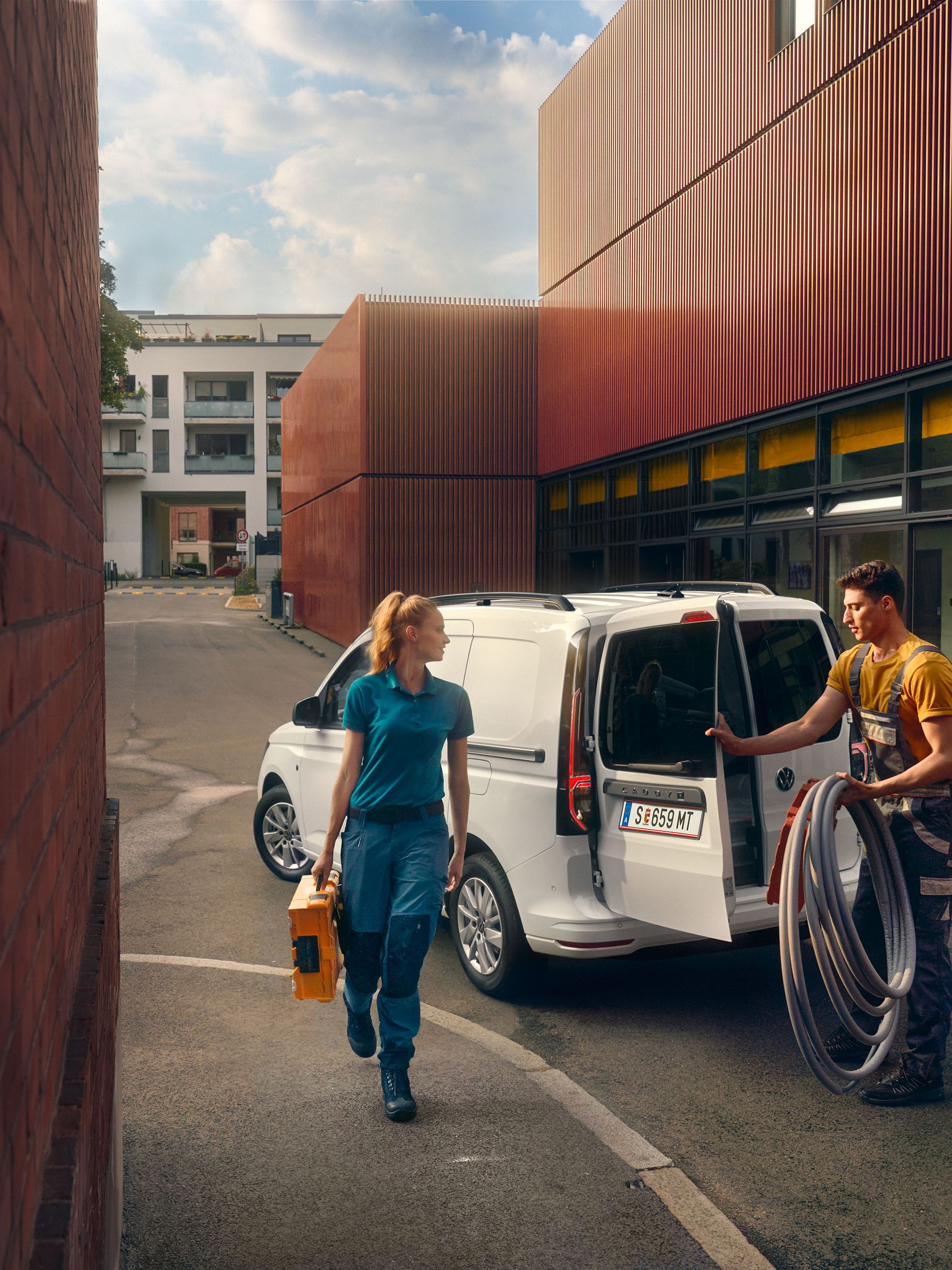 Handwerker Team räumt einen weißen Caddy Cargo aus.