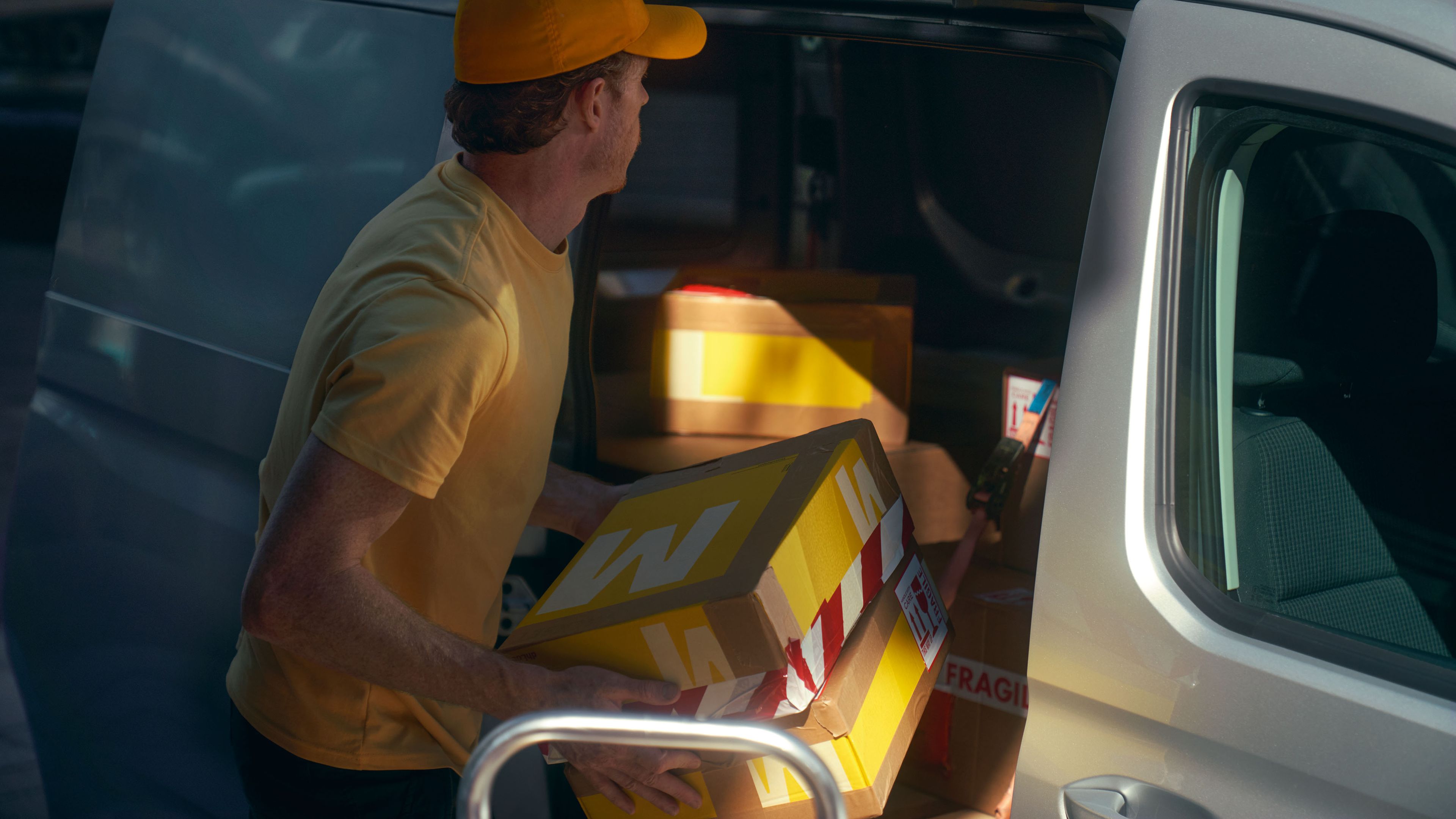 Ein Mann belädt einen weißen Caddy Cargo durch die Schiebetür.