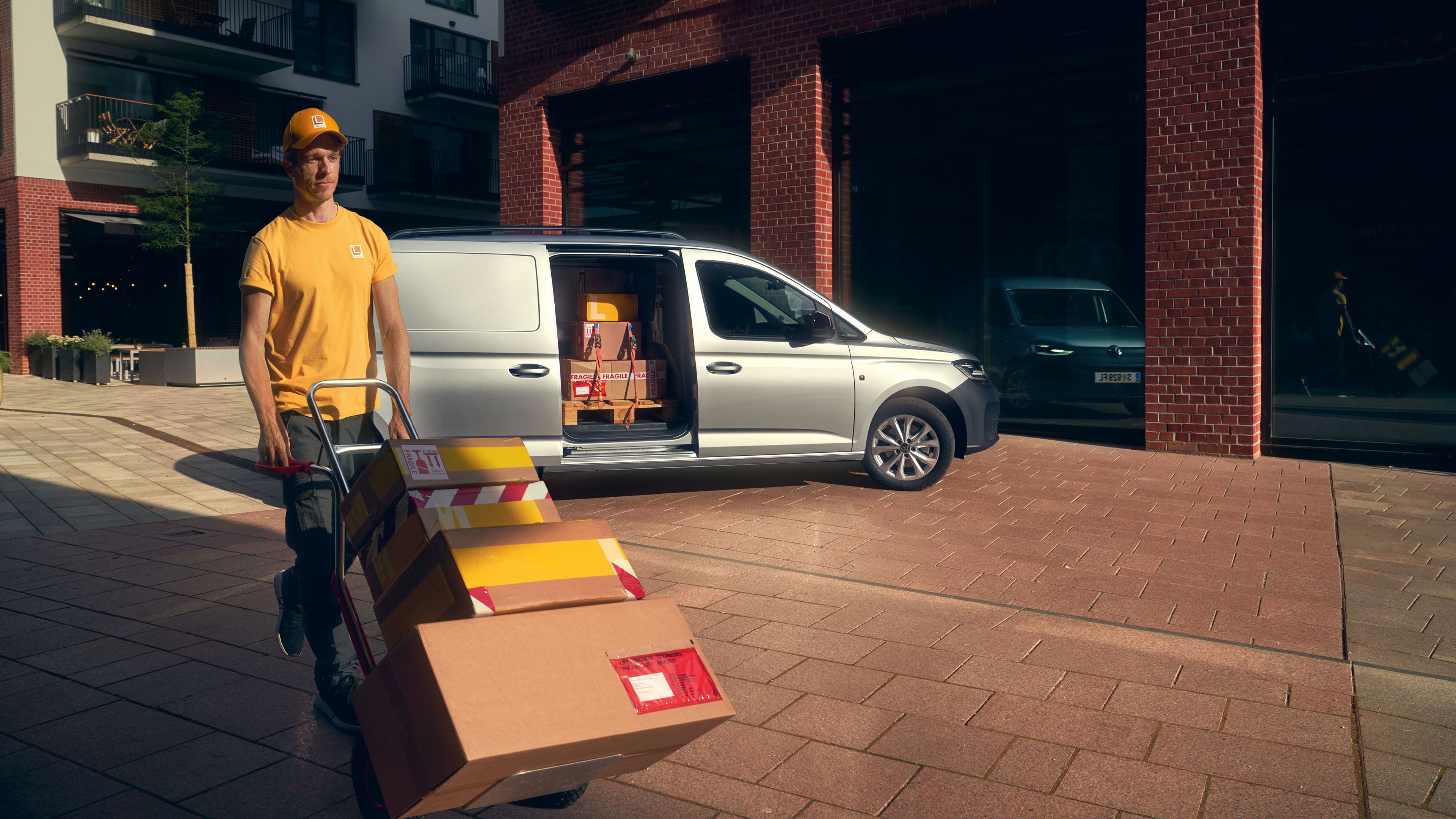 Ein VW Caddy Cargo Maxi steht vor einem Gebäude und wird entladen.