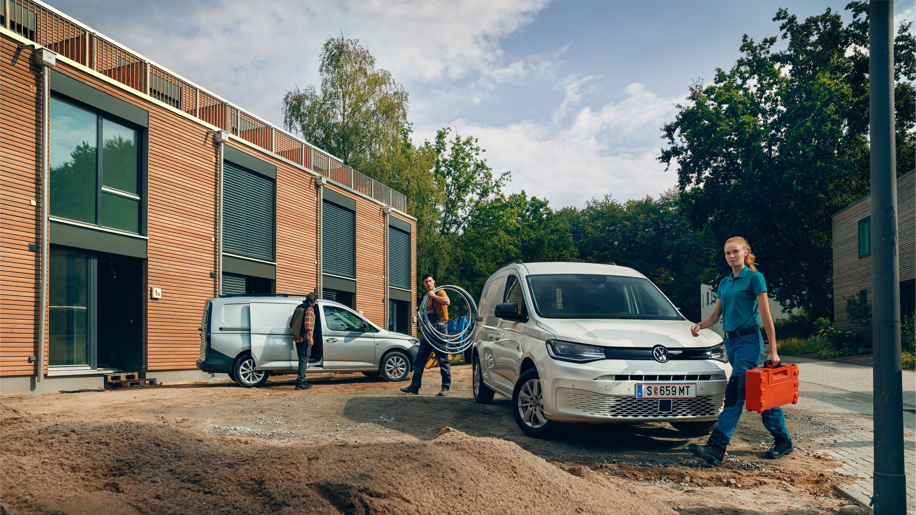 Ein weißer VW Caddy Cargo steht vor einer Baustelle.