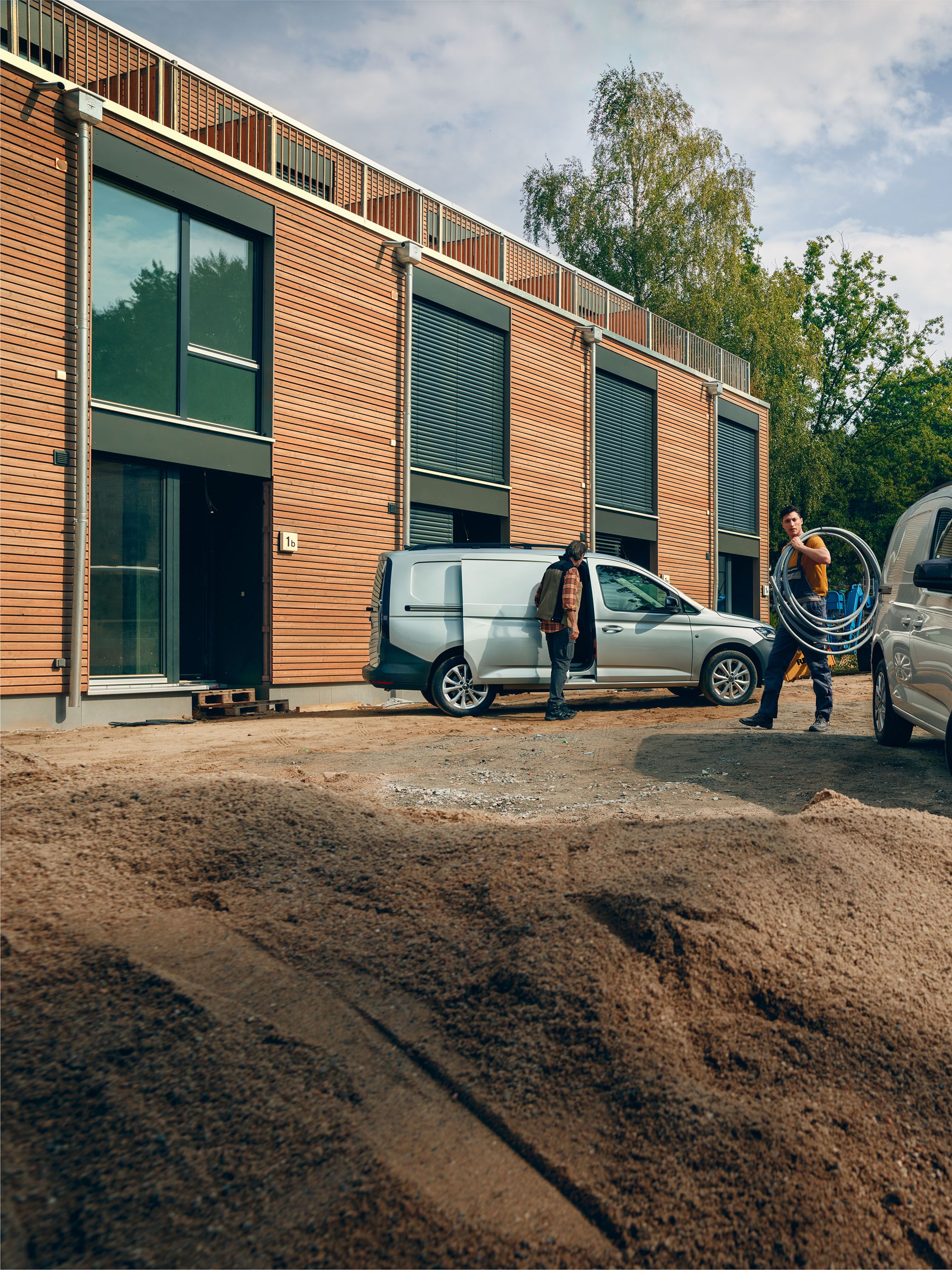 Ein weißer VW Caddy Cargo steht vor einer Baustelle.