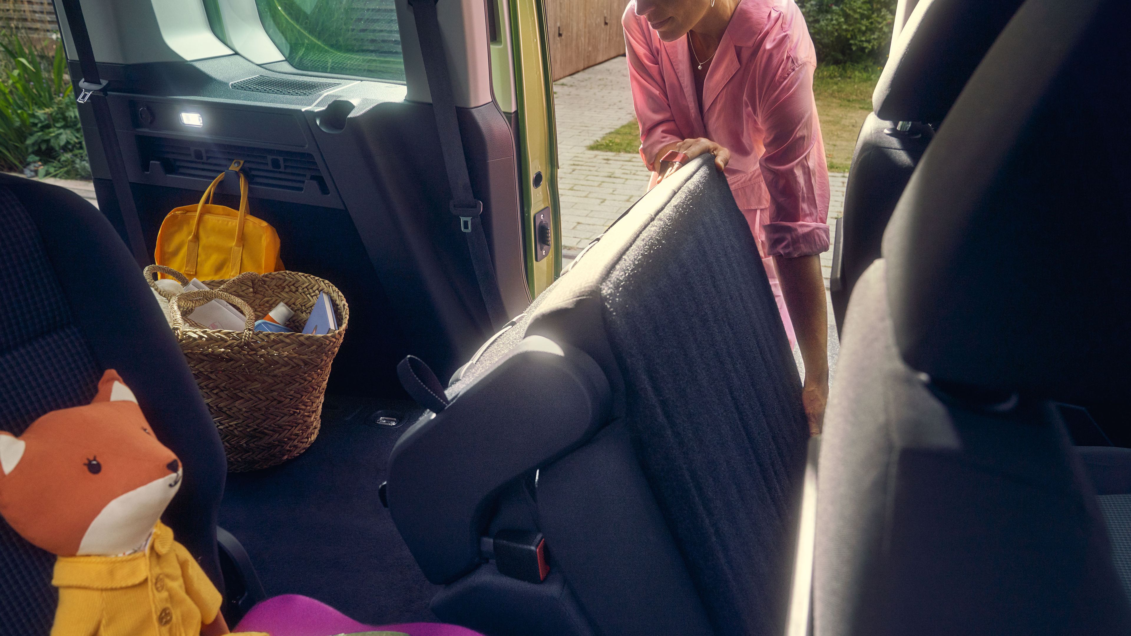 Eine Frau legt die Sitze in der zweiten Sitzreihe eines VW Caddy um.
