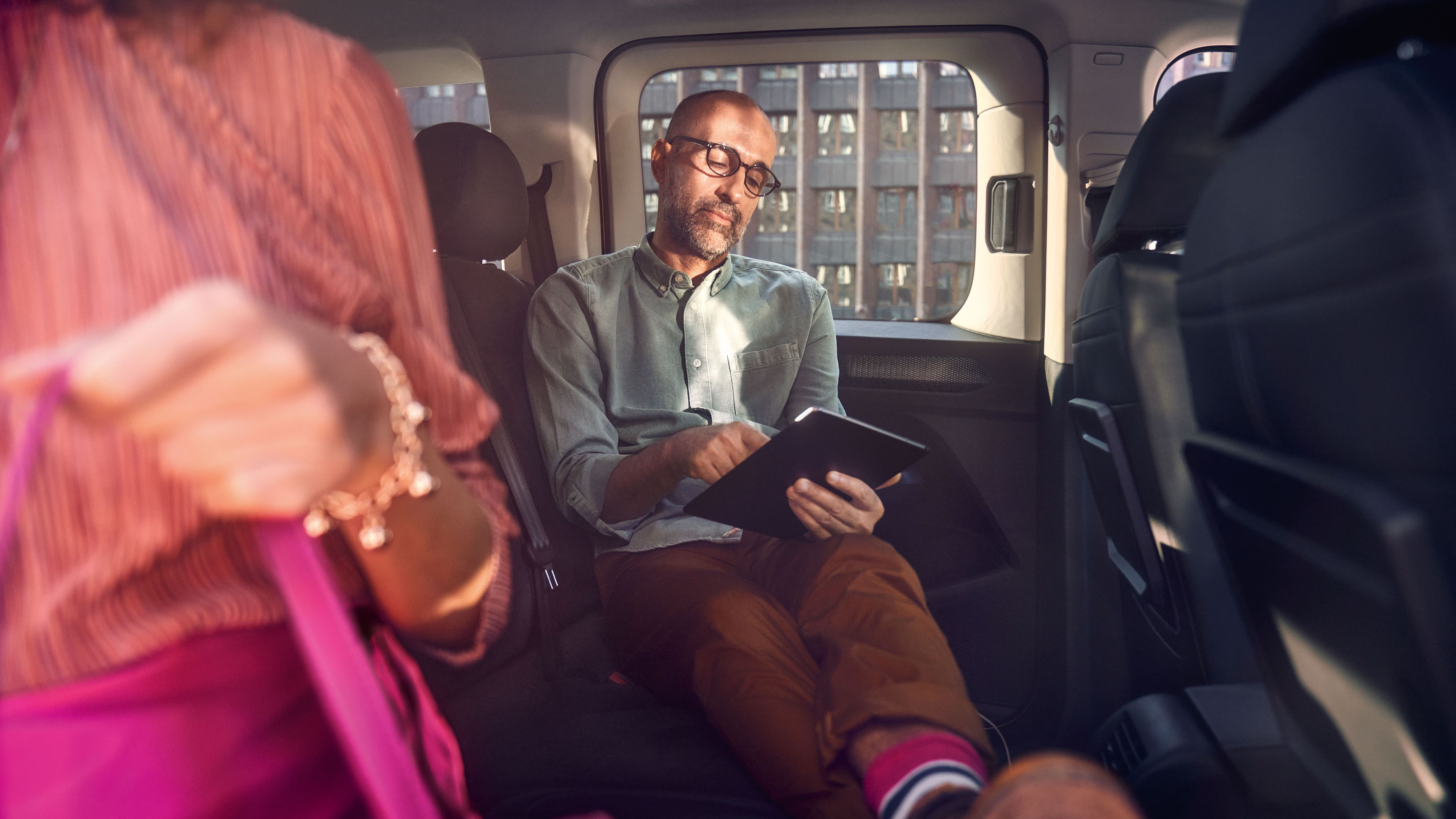 Ein Mann sitzt quer über die zweite Sitzreihe in einem VW Caddy mit den Füßen auf den Sitzen.